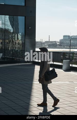 African young man in coat walking on the street outdoors Stock Photo