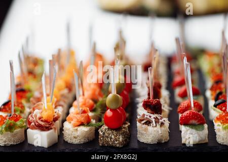 Delicious appetizers and canapes on table at wedding reception in the restaurant. Luxury catering service. Italian delicatessen, prosciutto snacks Stock Photo