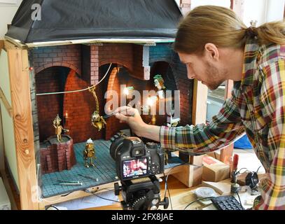 15 May 2021, Saxony, Leipzig: Leipzig computer science student and filmmaker Valentin Felder prepares miniature props in his small studio for his half-hour film 'Gears in the Sand'. 27-year-old stop-motion filmmaker with this project, in which he brings heartless humans and sentient robots to life in an imaginative story Thousands of parts ranging from 0.5 millimeters to a few centimeters in size made of copper, brass, wood, steel, plaster or Styrofoam have already been turned, filed, soldered and milled for this purpose, among other things for his robots and machines. He documents the develop Stock Photo