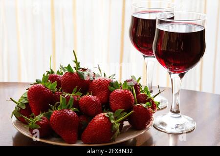 wine made from berries. Fresh ripe strawberries and glasses of red wine in the background. Summer alcoholic beverages Stock Photo