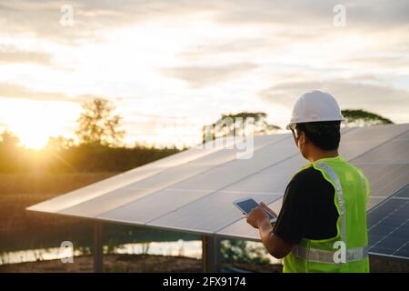 The solar farm or solar panel with Solar cell engineer using a tablet check and maintenance equipment at industry solar power, Photovoltaic module ide Stock Photo