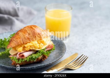Breakfast croissant sandwich with ham and scrambled eggs on a plate. Continental breakfast food Stock Photo