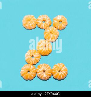Creative layout of the letter Z from peeled tangerines on a blue background. Flatlay. Stock Photo
