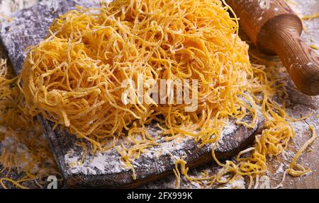 Tagliatelle pasta is thin. Traditional Italian named Angel Hair , capellini d'angels. Italian egg pasta, homemade and fresh in flour on a cutting table.  Stock Photo
