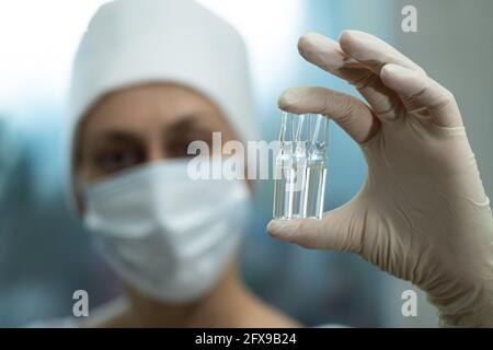 The doctor looks at the medical ampoule in his hand. Stock Photo