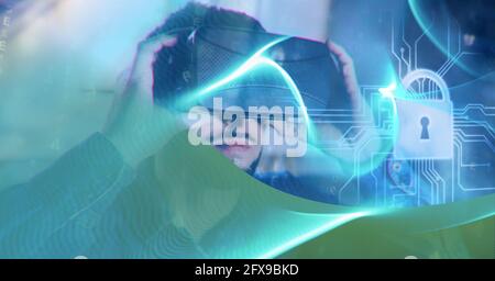 Composition of blue light trails and online security padlock over man wearing vr headset Stock Photo