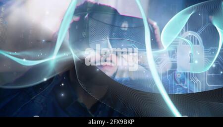 Composition of blue light trails and online security padlock over man wearing vr headset Stock Photo