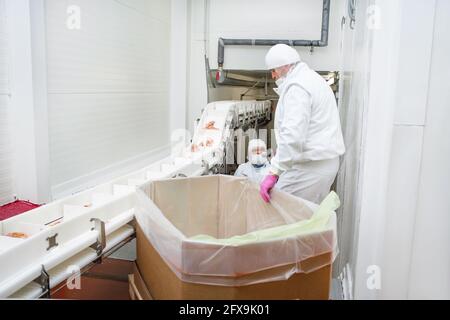 Chicken feet, chicken feet that are cut into many pieces in a large box.Line for the production of meat with packaging and cutting . Industrial equipm Stock Photo