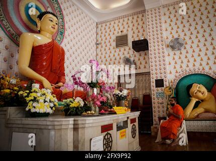 Kuala Lumpur, Malaysia. 26th May, 2021. A Buddhist monk wearing a face mask prays in an empty Buddhist temple during the Wesak Day celebration.The Wesak day, commemorates the birth, enlightenment and the passing away of Gautama Buddha, celebrated by Buddhists around the world. Malaysian has adopted a new way of celebrating Wesak Day with the Movement Control Order enforcement, all social and religious gathering are strictly prohibited. Credit: SOPA Images Limited/Alamy Live News Stock Photo