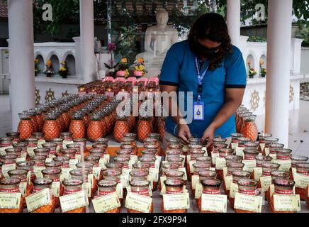 Kuala Lumpur, Malaysia. 26th May, 2021. A devotee wearing a face mask adjusting oil lamps in an empty Buddhist temple during the Wesak Day celebration.The Wesak day, commemorates the birth, enlightenment and the passing away of Gautama Buddha, celebrated by Buddhists around the world. Malaysian has adopted a new way of celebrating Wesak Day with the Movement Control Order enforcement, all social and religious gathering are strictly prohibited. Credit: SOPA Images Limited/Alamy Live News Stock Photo