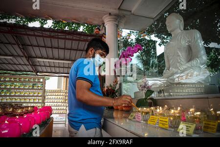 Kuala Lumpur, Malaysia. 26th May, 2021. A devotee wearing a face mask lights an oil lamp in an empty Buddhist temple during the Wesak Day celebration.The Wesak day, commemorates the birth, enlightenment and the passing away of Gautama Buddha, celebrated by Buddhists around the world. Malaysian has adopted a new way of celebrating Wesak Day with the Movement Control Order enforcement, all social and religious gathering are strictly prohibited. (Photo by Wong Fok Loy/SOPA Images/Sipa USA) Credit: Sipa USA/Alamy Live News Stock Photo