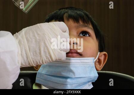 Sungai Buloh, Malaysia. 26th May, 2021. A health worker wearing a personal protective equipment suit (PPE) is seen taking a nasal swab sample from a child during the COVID19 testing at a test center in Sungai Buloh. Malaysia has recorded the highest daily cases of Covid-19, yesterday with a record of 7,289 cases. Selangor government continues to conduct mass COVID19 screening tests over the state to battle the coronavirus pandemic. (Photo by Faris Hadziq/SOPA Images/Sipa USA) Credit: Sipa USA/Alamy Live News Stock Photo