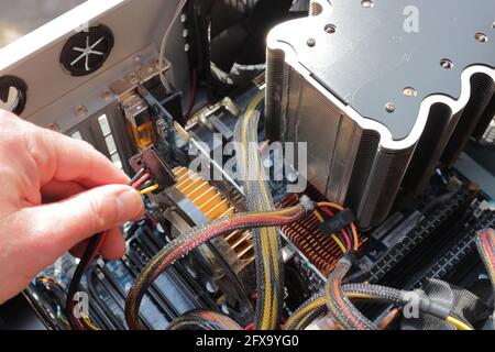 Hand about to connect a cable in a computer Stock Photo