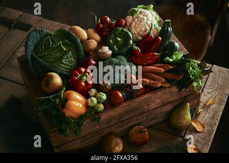 From above box with various fresh vegetables placed on timber table in rustic room Stock Photo