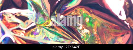Colorful glossy defocused hologram banner. Crumpled foil material. Pearlescent abstract texture. Stock Photo
