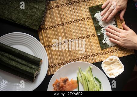 hands twist sushi rolls. close-up. japanese cuisine cooking method. top view Stock Photo