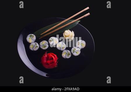 sushi roll yin yang in a black plate on a black background Stock Photo