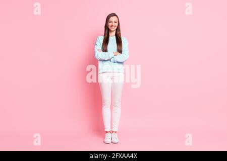 Full size photo of cheerful charming girl lovely smile crossed hands isolated on pastel pink color background Stock Photo