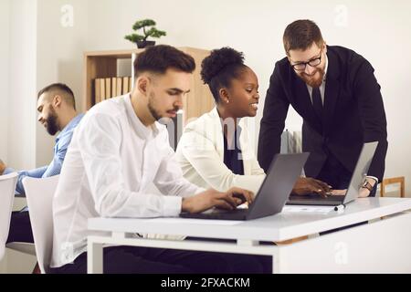 Diverse business people using laptop computers and working on digital projects together Stock Photo