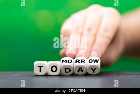 Hand turns dice and changes the word "today" to "tomorrow". Stock Photo