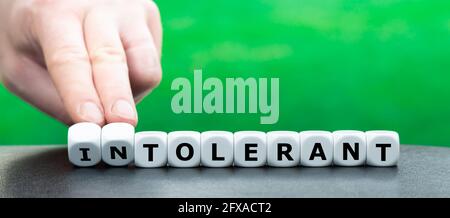 Hand turns dice and changes the word "intolerant" to "tolerant". Stock Photo