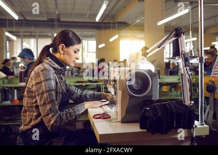 Shoe or clothing factory worker working at a table with an industrial sewing machine Stock Photo