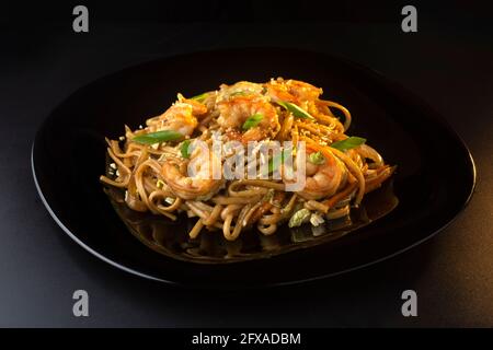 noodles with paste, shrimp and herbs on black plate Stock Photo