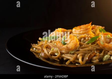 noodles with paste, shrimp and herbs on black plate, macro Stock Photo