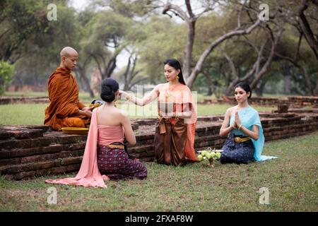 Thai woman pay homage to a Buddhist monk in morning. Stock Photo