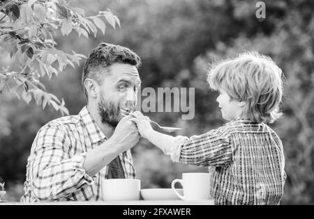 Feed your baby. Natural nutrition concept. Feeding son natural foods. Stage of development. Feed son solids. Dad and boy eat and feed each other Stock Photo