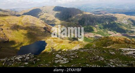 Clouds cast shadows on fells around Low Water below the Old Man of Coniston in Cumbria, England. Stock Photo