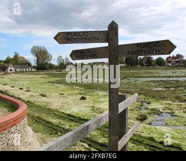 Public footpath signpost at Bosham Harbour village. Old school house is in the background. Stock Photo