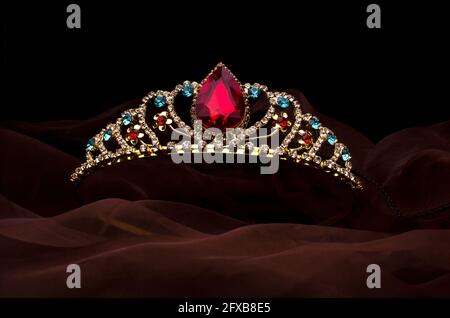 gold crown with red ruby stone isolated on the fabric Stock Photo