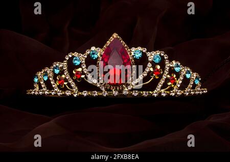 gold crown with red ruby stone isolated on the fabric Stock Photo