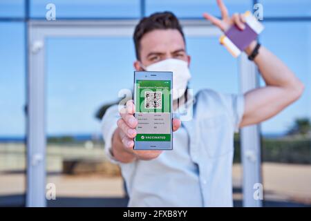 Hand man holding smartphone displaying an app mobile valid digital green vaccination certificate for Covid-19. Immunity vaccine passport, vaccination Stock Photo