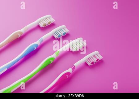 Four toothbrushes on a pink background in a row. Free space, isolate, top view Stock Photo