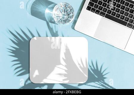 Laptop and mouse pad with sun shadow. Workplace flat lay. Mouse pad mockup for your design Stock Photo