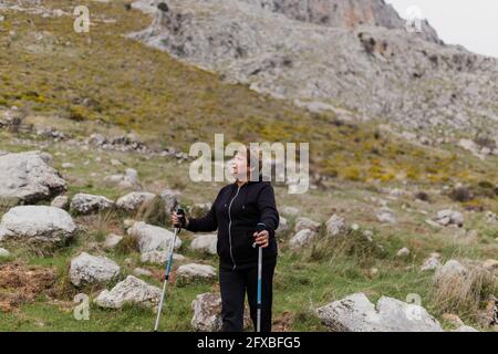 Senior woman in sports clothing hiking on mountain Stock Photo