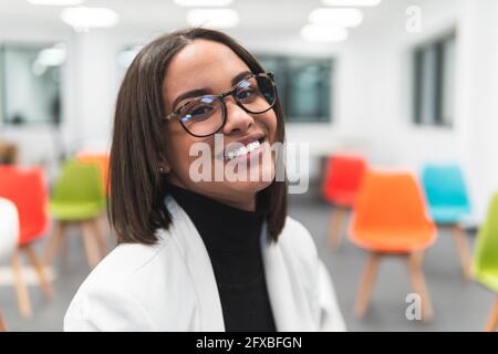 Businesswoman wearing eyeglasses smiling in classroom Stock Photo