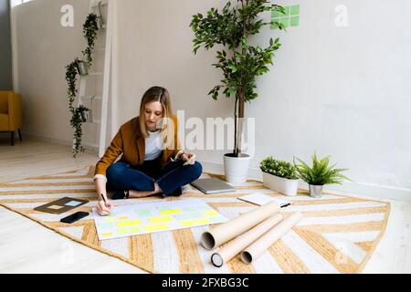 Businesswoman writing on adhesive note in office Stock Photo