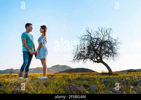 Young couple looking at each other while standing at meadow Stock Photo