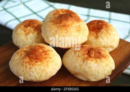 Closeup Heap of Homemade Brazilian Cheese Breads Called Pao de Queijo on Wooden Breadboard Stock Photo