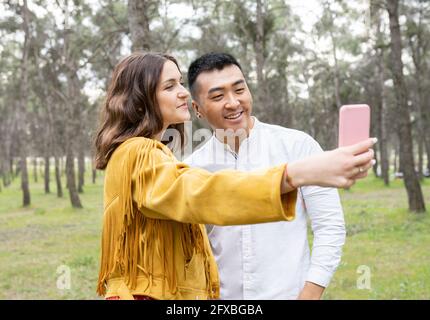 Man with beautiful woman taking selfie on smart phone at forest Stock Photo