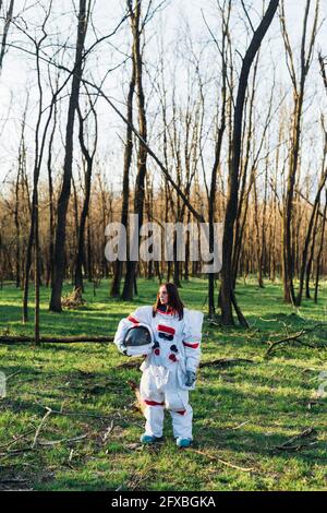 Female astronaut with space helmet standing in forest Stock Photo