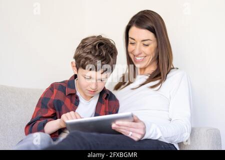 Boy using digital tablet by mother at home Stock Photo