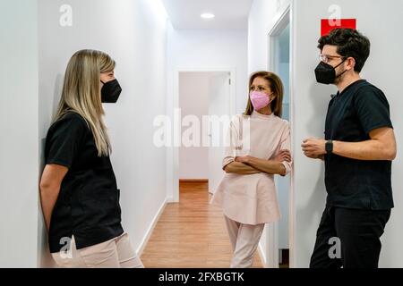 Female dentist discussing with male and female healthcare workers in clinic during pandemic Stock Photo