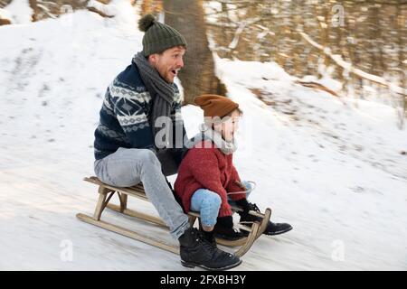 Father and son sledding during winter Stock Photo