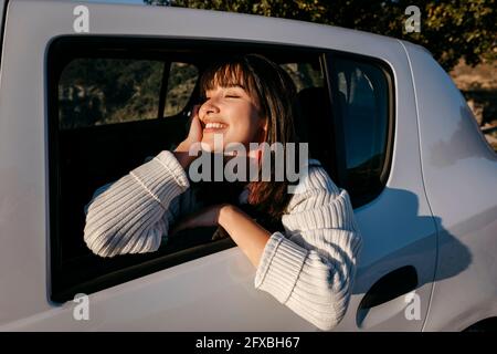 Smiling woman enjoying while traveling in car during road trip Stock Photo