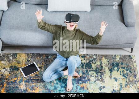 Cheerful woman gesturing while using virtual reality headset at home Stock Photo