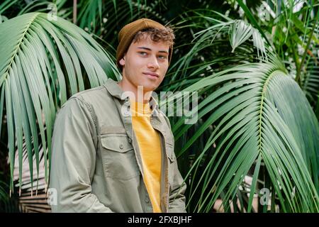 Smiling young man wearing knit hat standing at park Stock Photo